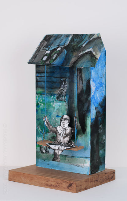 Artistic depiction of a figure on a swing with a blue and green background, mounted on a wooden base.